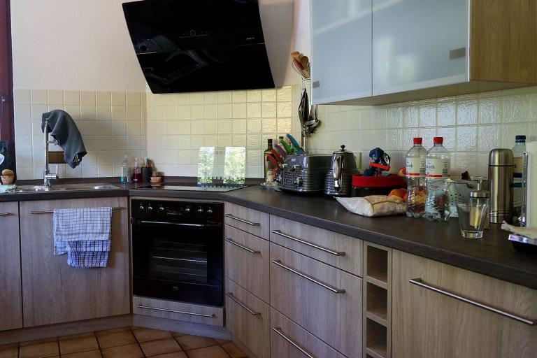 Naturholz-Küche mit dunklen Arbeitsflächen und halbtransparenten Hängeschrank-Türen