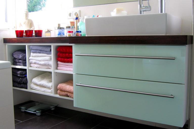 Waschtisch mit aufgesetztem Waschbecken, dunkler Ablage, Glasfront und Fächern