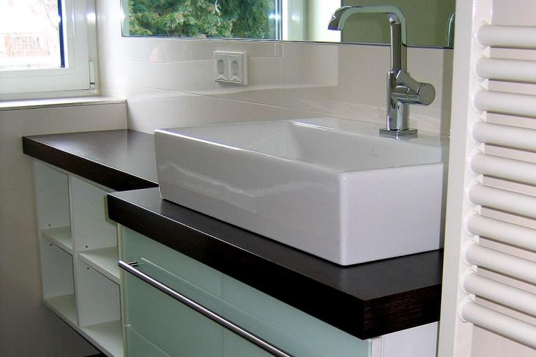 Waschtisch mit aufgesetztem Waschbecken, dunkler Ablage, Glasfront und Fächern