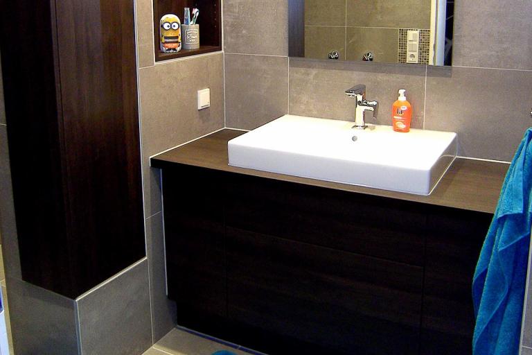 Dunkler Waschtisch mit aufgesetzem Waschbecken, eingelassenes Regal und Holz-Verkleidung