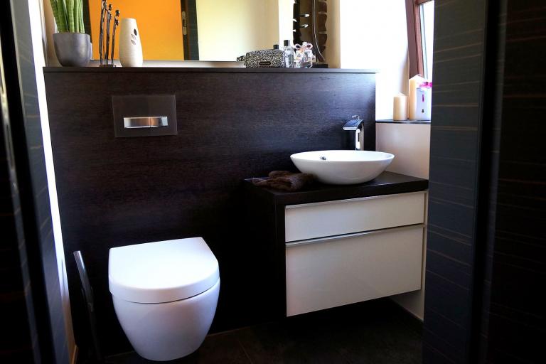 Waschtisch mit weißen Fronten und dunkler Wasserkasten-Verkleidung