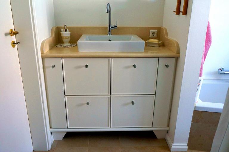 Waschtisch mit Holzplatte und weißer Front in einer Nische
