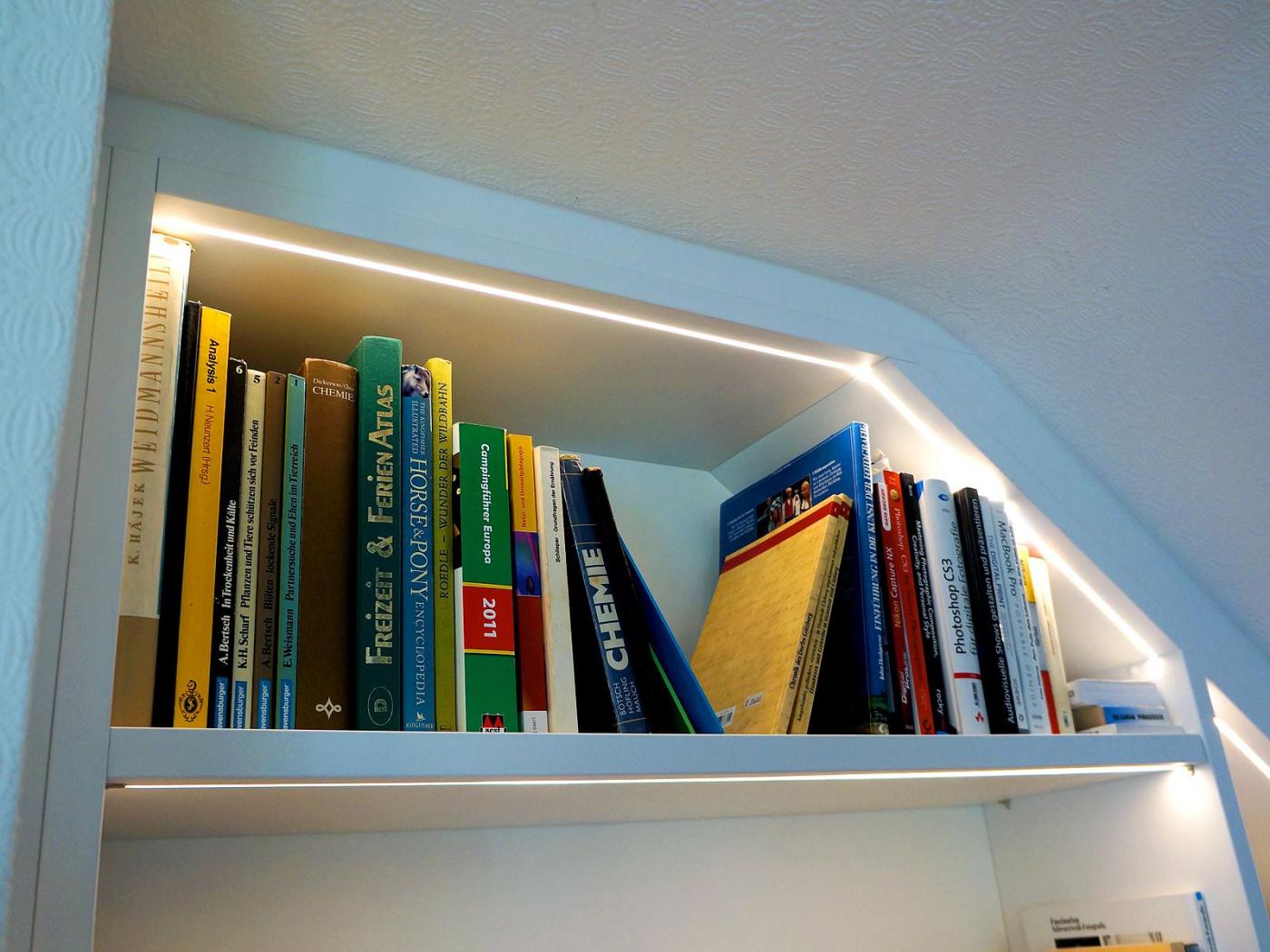 Bücherregal mit LED-Beleuchtung unter Dachschräge in der Nische