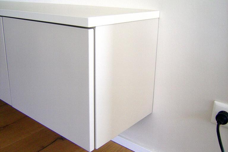 Weißes Sideboard mit Regal unter hängendem TV-Gerät