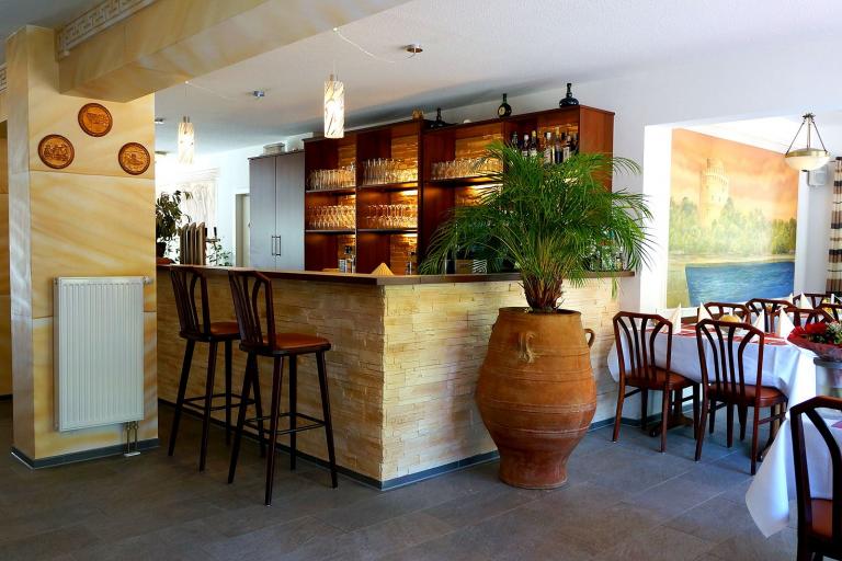 Theke, Tische, Stühle und beleuchtetes Gläser-Regal in einem Restaurant