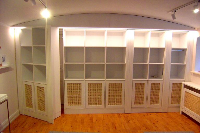 Wandregal mit beleuchteten Fächern und versteckter Durchgangstür zum Privatbereich